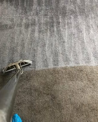 A grey carpet with the wand on the line between the cleaned and uncleaned part