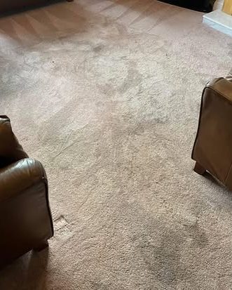 Beige lounge carpet with dark worn patches beside a leather chair