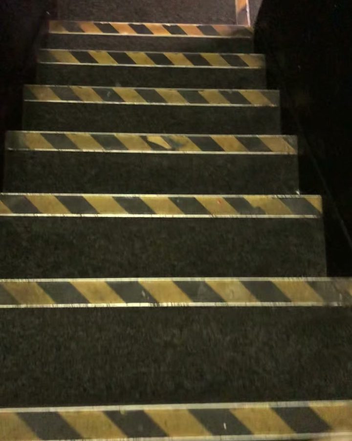 Dark stair carpet dull and dusty between yellow safety edges